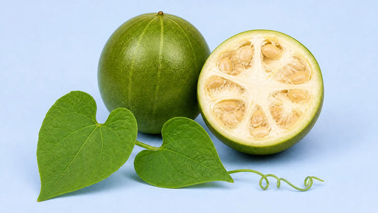 Whole green monk fruit and a halved fruit showing its seeds, with a vine sprig, two heart-shaped leaves and a tendril