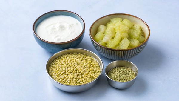 Bowls of curd, cooked lauki, soaked moong dal and a small katori of saunf on a pale tabletop