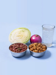 Rajma, boiled chana, half a cabbage, an onion and a fizzy drink on a pale table